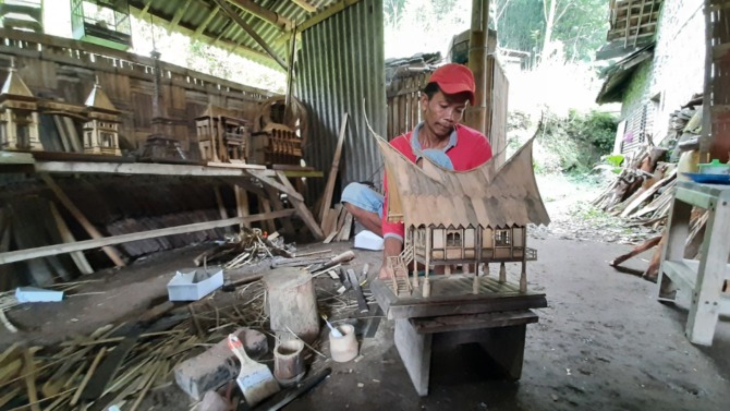 KREATIF: Waroni tengah menyelesaikan pesanan miniatur Pendapa Surya Graha yang terbuat dari bambu. (MAULANA RAIHAN/JAWA POS RADAR MAGETAN)