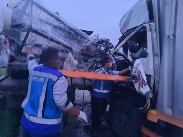 TABRAKAN BERUNTUN: Petugas berusaha mengevakuasi Samsul Bahri, kernet truk boks yang terjepit, usai kendaraannya menumbur truk muatan combine harvester di tol Soker Km 570.  (ISTIMEWA)