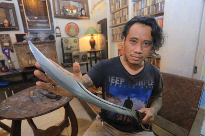 TAJAM: Tino Budiarto menunjukkan sebuah pedang buatannya. (BAGAS BIMANTARA/JAWA POS RADAR MADIUN)