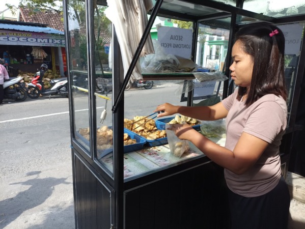 BERTAHAN: Pedagang gorengan di Jalan Panjaitan yang menjual dagangan lebih mahal imbas mahalnya harga minyak goreng. (FAIZAL AMJAD/JAWA POS RADAR NGAWI)