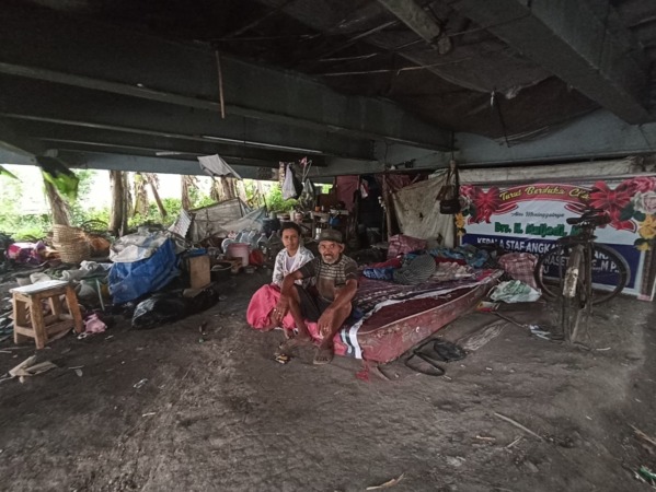 KUMUH: Misrin bersama Sri Wahyuti, istrinya, tinggal di kolong Jembatan Ring Road Timur Ngawi. (FAIZAL AMJAD/JAWA POS RADAR NGAWI)