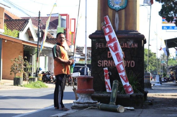 RONTEK: Warga membersihkan sisa kentongan bambu yang dibuang di tepi jalan. (SUGENG DWI N./JAWA POS RADAR PACITAN)