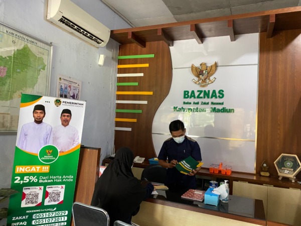 BAYAR: Seorang perempuan sedang membayar zakat di kantor Baznas Kabupaten Madiun kemarin (14/4). (M.R. AKROMU NIAM/JAWA POS RADAR CARUBAN)