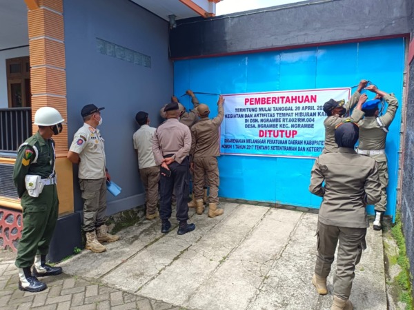 DISEGEL: Petugas gabungan memasang spanduk penutupan di pintu gerbang tempat karaoke milik HR kemarin. (SATPOL PP FOR JAWA POS RADAR NGAWI)