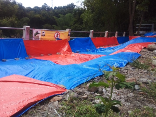 HANYA SEMENTARA: Retakan yang muncul di talut Kali Gandong kemarin (13/5) ditutup terpal untuk mencegah air masuk. (FAIZAL AMJAD/JAWA POS RADAR MAGETAN)