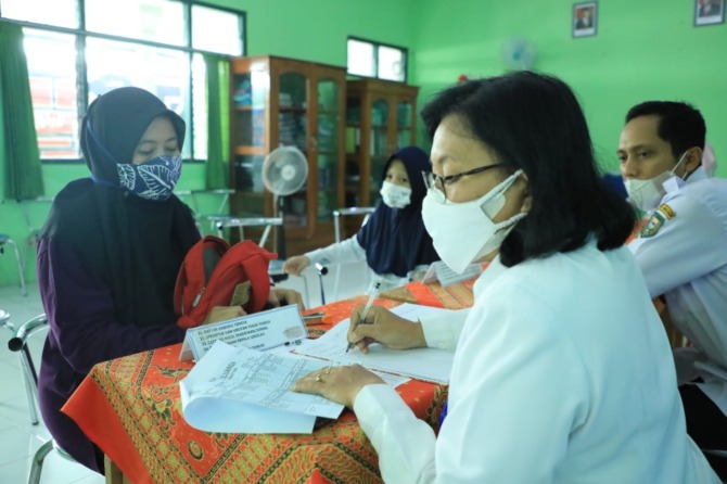 CARI SEKOLAH: Seorang siswa didampingi orang tuanya mendaftarkan diri via jalur offline di SMPN 14 Madiun kemarin (8/6). (DISKOMINFO FOR JAWA POS RADAR MADIUN)