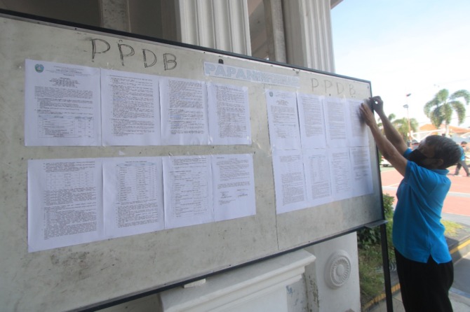 CARI SEKOLAH: Petugas sekolah menempelkan papan pengumuman terkait mekanisme PPDB SMP di Ponorogo kemarin (18/6). (AJI PUTRA/JAWA POS RADAR PONOROGO)