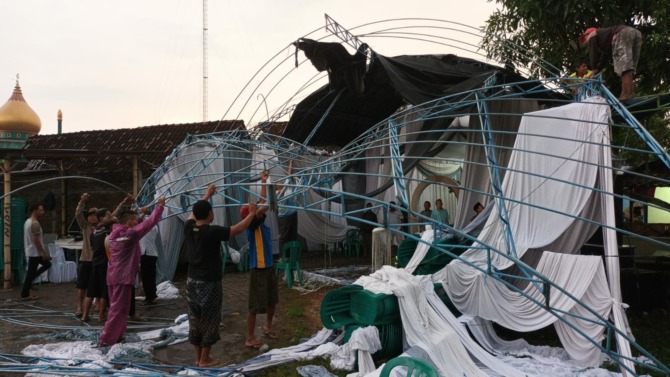 KERJA BAKTI: Sejumlah warga memperbaiki tenda pengantin di Desa Klitik yang tidak kuat menahan sapuan angin kencang. ((ASEP SYAEFUL BACHRI/JAWA POS RADAR NGAWI)