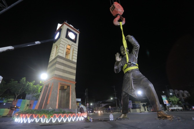 DIRAWAT: Alat berat dikerahkan untuk menurunkan patung pendekar dari atas tugu setinggi delapan meter. Sementara para pekerja melakukan penggantian as dinamo dini hari kemarin (8/7). (BAGAS BIMANTARA/JAWA POS RADAR MADIUN)