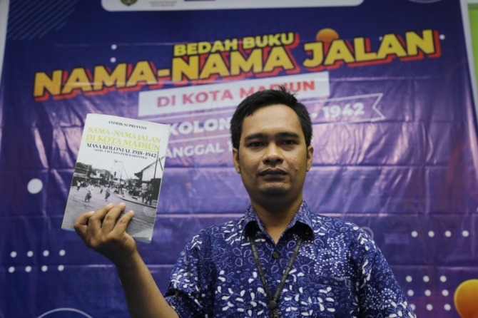 KUPAS SEJARAH: Andrik Suprianto menunjukkan buku karyanya berjudul Nama-Nama Jalan di Kota Madiun (Masa Kolonial 1918-1942). (BAGAS BIMANTARA/JAWA POS RADAR MADIUN)