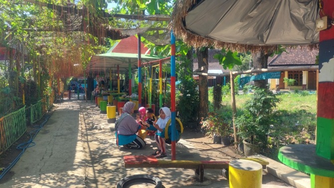 BERLIBUR: Sejumlah pengunjung sedang menikmati salah satu wahana permainan di desa wisata Taman Bantaran Kanal Poyo, Desa Banaran, Geger, Minggu (24/7). (DIAN RAHAYU/TRAINING JAWA POS RADAR MADIUN)