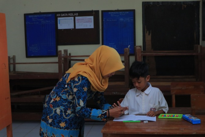 MENGABDI: Salah seorang guru saat mengajar muridnya di sekolah dasar. (SUGENG DWI N./JAWA POS RADAR PACITAN)