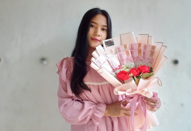 KREATIF: Rona Puspita menunjukkan salah satu buket uang hasil kreasinya. (RAHMA DWI LESTARI/JAWA POS RADAR MADIUN)