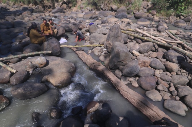 EVAKUASI: Sejumlah warga menggali bongkahan batu yang menjepit sebuah balok kayu di aliran Sungai Andong, Jogorogo. Benda itu diduga bagian dari perahu lesung abad ke-15. (R BAGUS RAHADI/JAWA POS RADAR NGAWI)