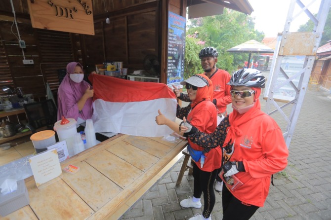 SAMBUT HARI KEMERDEKAAN RI: Para pengurus DHC 45 Kota Madiun gowes sambil membagikan bendera ke para pedagang di lapak UMKM kelurahan. (BAGAS BIMANTARA/RADAR MADIUN)
