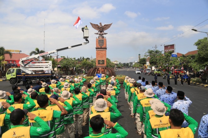 KHIDMAT: Sebanyak 77 petugas pertamanan dan PJU Dinas Perkim Kota Madiun menggelar upacara di depan Tugu Pancasila. (BAGAS BIMANTARA/JAWA POS RADAR MADIUN)