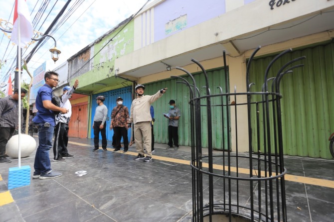 SIDAK: Wali Kota Maidi menandai lantai keramik pedestrian Jalan Panglima Sudirman dengan cat semprot putih kemarin (18/8). Titik itu penanda lokasi pemasangan kursi. (BAGAS BIMANTARA/JAWA POS RADAR MADIUN)