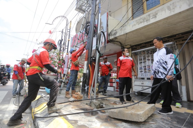 DIRINGKAS: Kepala DPUPR Kota Madiun Suwarno mengawasi penertiban tiang jaringan utilitas kabel udara dengan cara dipendam di bawah tanah (ducting) di Jalan Panglima Sudirman kemarin (19/8). (BAGAS BIMANTARA/JAWA POS RADAR MADIUN)