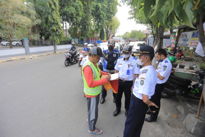 MASUK KANTONG PRIBADI: Petugas gabungan dishub, satpol PP, dan Satlantas Polres Madiun Kota mendata juru parkir liar di Jalan D.I. Panjaitan kemarin (25/8). (BAGAS BIMANTARA/RADAR MADIUN)