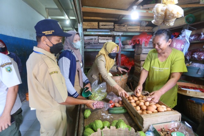 SIDAK: Petugas Disdag Kota Madiun memantau harga bahan pokok di Pasar Sleko kemarin (30/8). (BAGAS BIMANTARA/JAWA POS RADAR MADIUN)