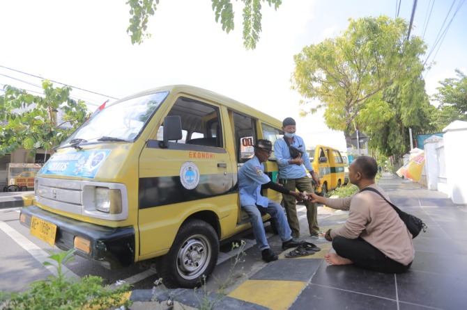 KENA DAMPAK: Para pengemudi angkutan kota tengah bersantai sembari menunggu penumpang kemarin (30/8). Sektor transportasi angkutan umum dan ojek, termasuk kelompok penerima bansos pengalihan subsidi BBM. (BAGAS BIMANTARA/JAWA POS RADAR MADIUN)