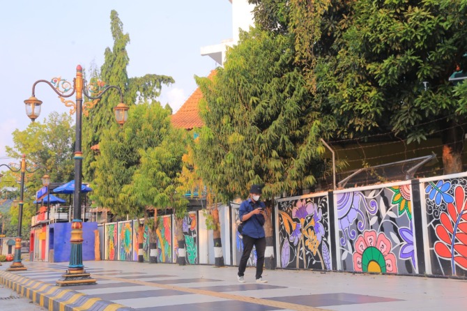LEBIH CANTIK: Tembok di sepanjang Jalan Rimba Dharma dimural dengan tema Madiun Kota Sejuta Bunga kemarin (12/9). (BAGAS BIMANTARA/JAWA POS RADAR MADIUN)