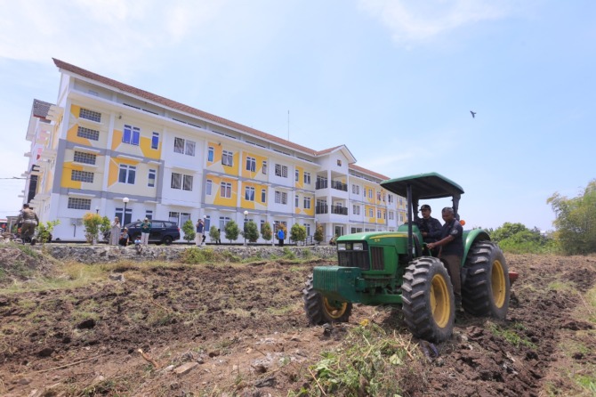 TEKAN INFLASI: Wali Kota Madiun Maidi mengemudikan traktor untuk mengolah lahan tidur di selatan rusunawa II, Sabtu (17/9). Pemkot Madiun memanfaatkan aset ini untuk lahan pertanian. (BAGAS BIMANTARA/JAWA POS RADAR MADIUN)