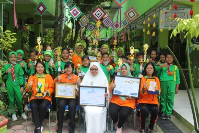 PRESTASI: Kepala SDN 03 Madiun Lor Jasmi bersama guru dan siswa menunjukkan beberapa penghargaan yang diraih sekolahnya. (ABRIANTO WIBOWO/JAWA POS RADAR MADIUN)