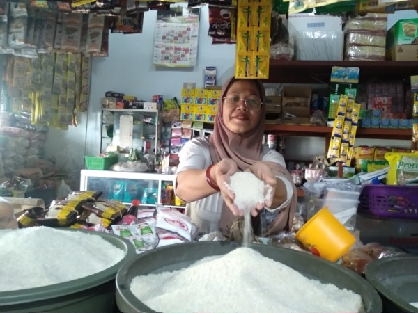 BIKIN SUSAH: Lilindari, salah seorang pedagang di Pasar Kojo, Kanigoro, Kartoharjo, menunjukkan beras super di lapaknya yang harganya melambung tinggi. (RAHMA DWI LESTARI/JAWA POS RADAR MADIUN)