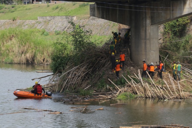 CEGAH BANJIR: Petugas BPBD Kota Madiun dan personel Yonif Para Raider 501/Bajra Yudha membersihkan sampah yang nyangkut di fondasi dan pilar jembatan Manguharjo. (BAGAS BIMANTARA/JAWA POS RADAR MADIUN)