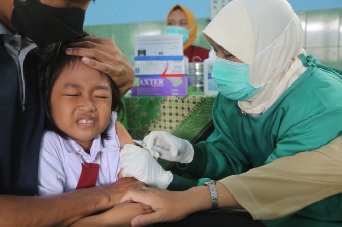 PERLINDUNGAN: Seorang siswa SDN Banjarejo sedang menjalani imunisasi. Dinkes PPKB gerilya menggenjot capaian imunisasi MR. (BAGAS BIMANTARA/JAWA POS RADAR MADIUN)