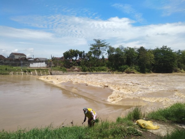 KIRIMAN TETANGGA: Debit air Bengawan Madiun terpantau meninggi di bantaran kawasan jembatan Manguharjo kemarin (23/10). (RAHMA DWI LESTARI/JAWA POS RADAR MADIUN)