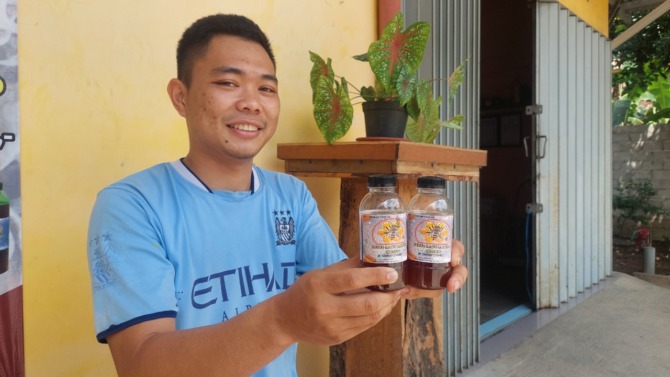 TEKUN: Ilham Adilla menunjukkan hasil produksi madu dan salah satu kotak sarang lebah miliknya. (DIAN RAHAYU/JAWA POS RADAR CARUBAN)