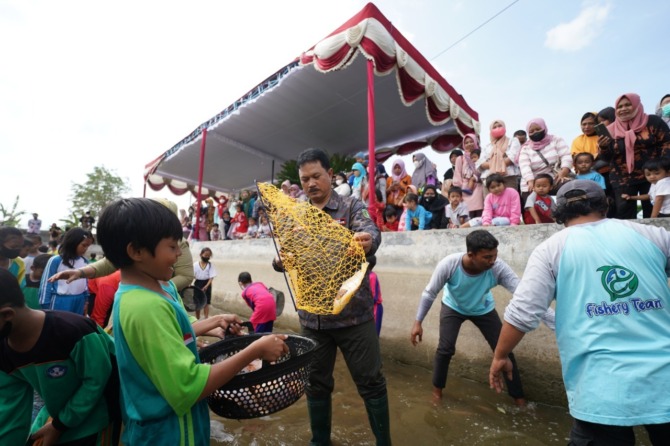 EDUKATIF: Wali Kota Madiun Maidi bersama Ketua TP PKK Yuni Setyawati Maidi menjaring ikan bersama anak-anak di kolam ikan Dinas Ketahanan Pangan dan Pertanian. (DISKOMINFO FOR JAWA POS RADAR MADIUN)