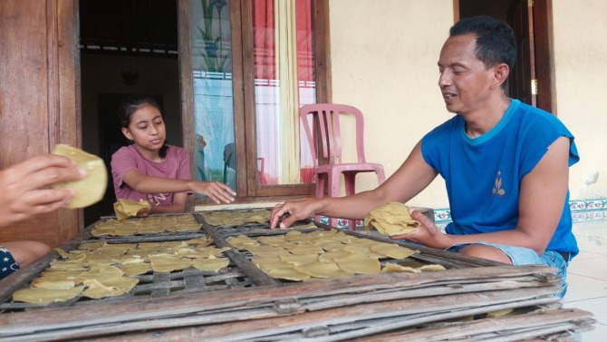 TURUN TEMURUN: Agus Fitrianto saat menjemur kerupuk terasi Tawang di depan rumahnya. (DIAN RAHAYU/JAWA POS RADAR MADIUN)