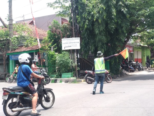PENERTIBAN: Salah seorang jukir sedang memberi aba-aba kendaraan di kawasan Sleko, kemarin (4/11). (RAHMA DWI LESTARI/JAWA POS RADAR MADIUN)