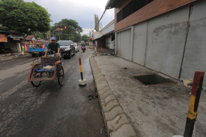 DISAMBUNG: Proyek normalisasi saluran air dan pembangunan trotoar-pedestrian tambahan di Jalan Mayjen Sungkono dikerjakan DPUPR Kota Madiun. (BAGAS BIMANTARA/JAWA POS RADAR MADIUN)