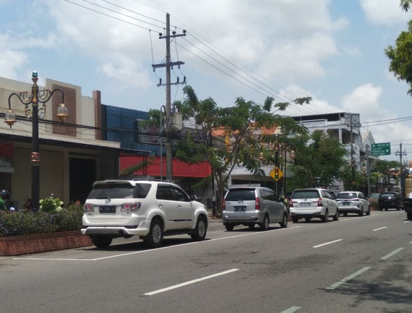 GENJOT PAD: Sejumlah kendaraan roda empat parkir di tepi Jalan H.A. Salim kemarin (2/11). Pendapatan retribusi parkir tahun ini naik. (RAHMA DWI LESTARI/JAWA POS RADAR MADIUN)