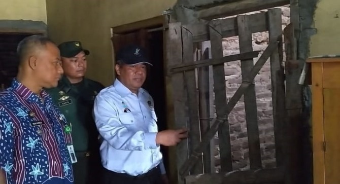 MIRIP KERANGKENG: Petugas Dinas Sosial membuka paksa pintu kamar AW, warga Desa Ngetrep, Jiwan, kemarin (1/12). (ISTIMEWA)