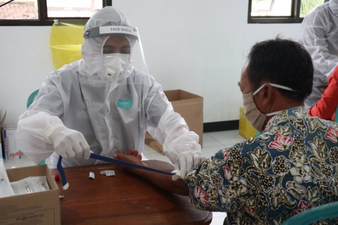 GARDA DEPAN: Seorang tenaga kesehatan melakukan skrining kepada seorang warga sebelum menjalani vaksinasi Covid-19. (DOKUMEN JAWA POS RADAR PACITAN)