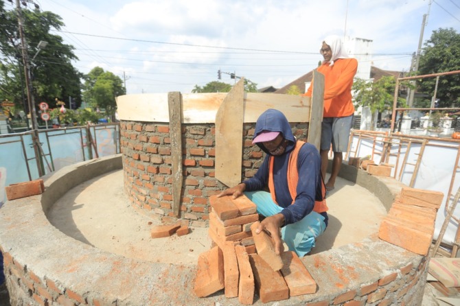MAKIN CANTIK: Pekerja tengah mengerjakan pembangunan planter patung penjual-pembeli pecel di simpang empat Jalan Pahlawan, Sabtu (3/12). (BAGAS BIMANTARA/JAWA POS RADAR MADIUN)