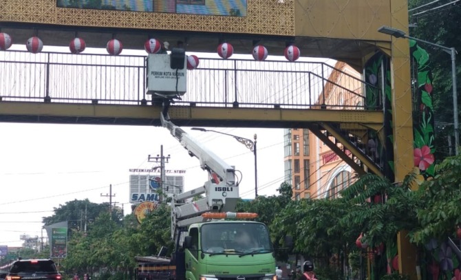 PEMELIHARAAN: Petugas disperkim memperbaiki lampu PJU dan lampion di Jalan Pahlawan Kota Madiun, Rabu (14/12). (RAHMA DWI LESTARI/JAWA POS RADAR MADIUN)
