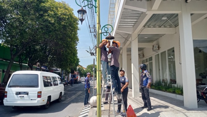 MAINTENANCE: Petugas dishub melakukan perbaikan PJU di Jalan Yos Sudarso Magetan, Desember lalu. (DOK RADAR MAGETAN)