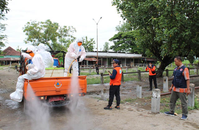PENGENDALIAN KASUS: Petugas BPBD Jatim dan Ngawi melakukan penyemprotan disinfektan ke salah satu pasar hewan kemarin. (BPBD UNTUK JAWA POS RADAR NGAWI)