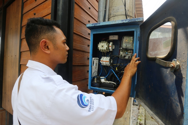 TERKONEKSI INTERNET: Salah seorang petugas Diskominfo Kota Madiun memeriksa peranti on-off braker di panel PJU kawasan Jalan Pahlawan kemarin (24/1). (BAGAS BIMANTARA/JAWA POS RADAR MADIUN)