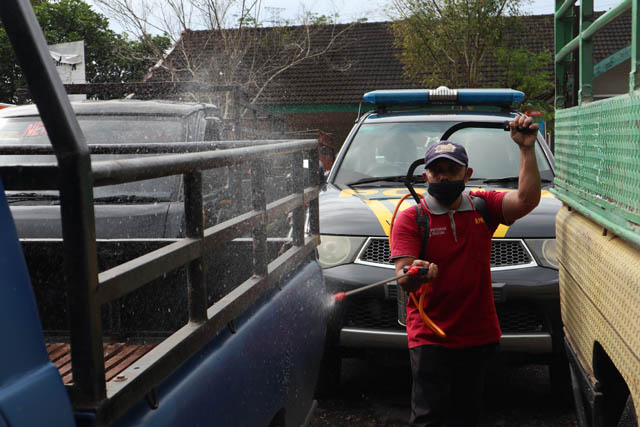 AWAS PMK: Petugas Dinas Ketahanan Pangan dan Pertanian Pacitan melakukan penyemprotan disinfektan ke kendaraan pengangkut hewan sebelum masuk ke Pasar Pon Semanten kemarin (27/1). (SUGENG DWI N/RADAR PACITAN)