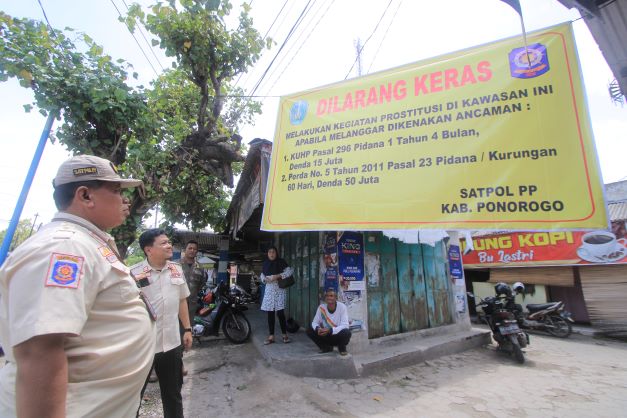 BAKAL DITUTUP: Petugas memasang spanduk peringatan agar tidak bertindak asusila di Pasar Janti. (AJI PUTRA/JAWA POS RADAR PONOROGO)