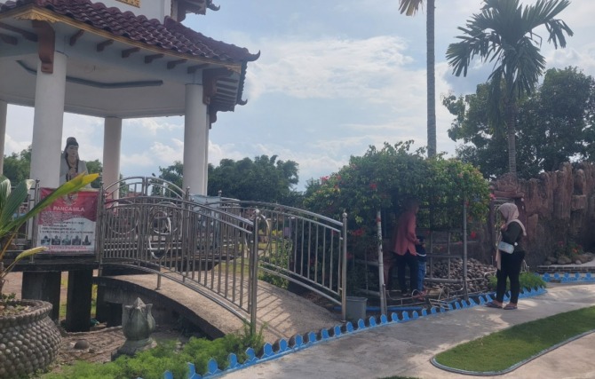 RAMAI: Seorang pengunjung sedang berada di dekat minatur kelenteng di tempat ibadah lima agama Desa Bulakrejo, Balerejo, kemarin. (DIAN RAHAYU/JAWA POS RADAR MADIUN)