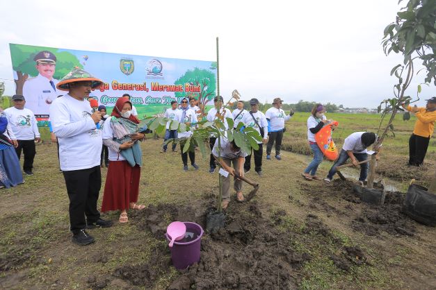 MANFAATKAN LAHAN: Wali Kota Madiun Maidi bersama siswa-siswi dan bayi menanam pohon di kawasan lahan Peceland kemarin (1/1). (BAGAS BIMANTARA/JAWA POS RADAR MADIUN)