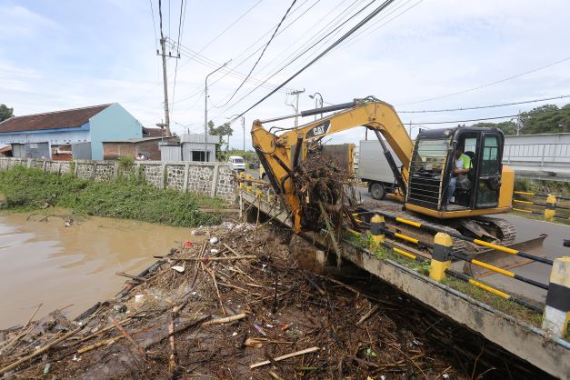 PENYEBAB BANJIR: Petugas DPUPR dan BPBD mengangkat sampah dan bambrongan yang nyangkut di bawah Jembatan Buk Malang kemarin (18/1). (BAGAS BIMANTARA/JAWA POS RADAR MADIUN)